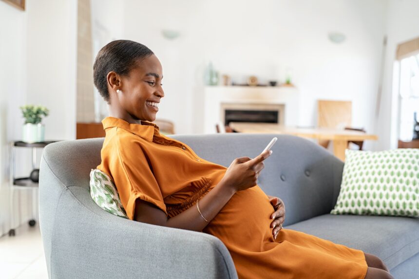 Pregnant african woman using smartphone at home